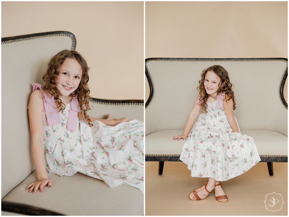indoor studio portrait session with a little girl in a white dress covered in pink flowers. 