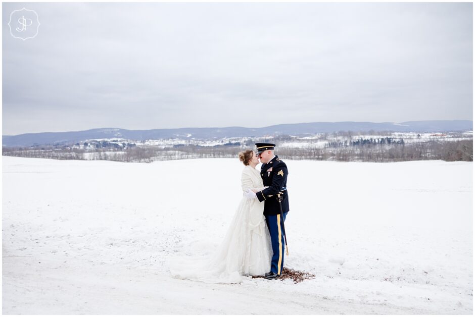 A snow covered field panoramic view of Saint Vincent with a couple posing together for their wedding photos 
