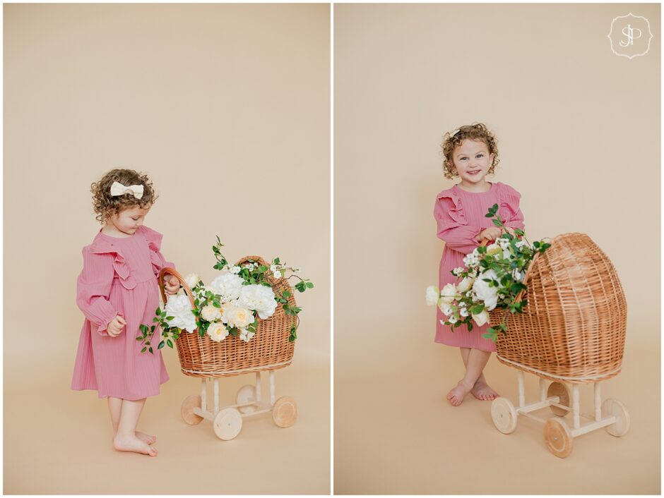 Little girl in light pink with a pram and flowers at a Latrobe photography studio spring time birthday portraits.